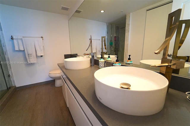 bathroom with hardwood / wood-style flooring, vanity, toilet, and a shower with shower door