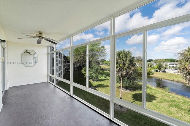 unfurnished sunroom featuring a water view, ceiling fan, and a healthy amount of sunlight