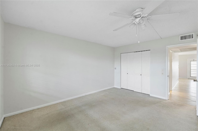 unfurnished bedroom featuring light colored carpet, ceiling fan, and a closet