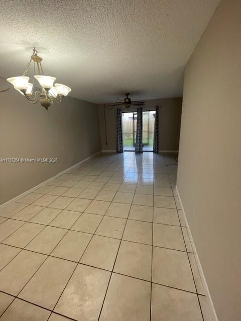 20810 NE 8th Ct Unit 104-18, Miami, FL 33179 - empty room featuring light tile patterned flooring, ceiling fan with notable chandelier, and a textured ceiling