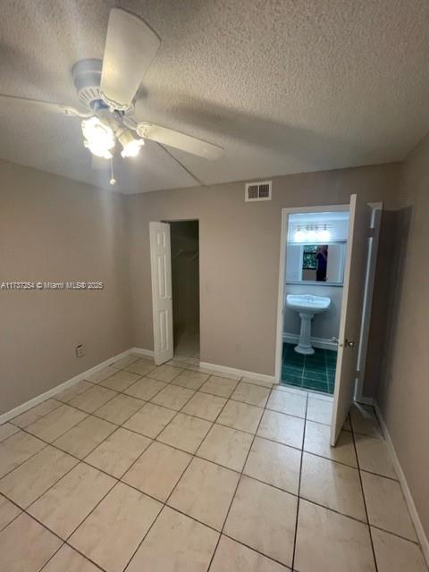 20810 NE 8th Ct Unit 104-18, Miami, FL 33179 - unfurnished bedroom featuring ensuite bathroom, a closet, a textured ceiling, and light tile patterned flooring