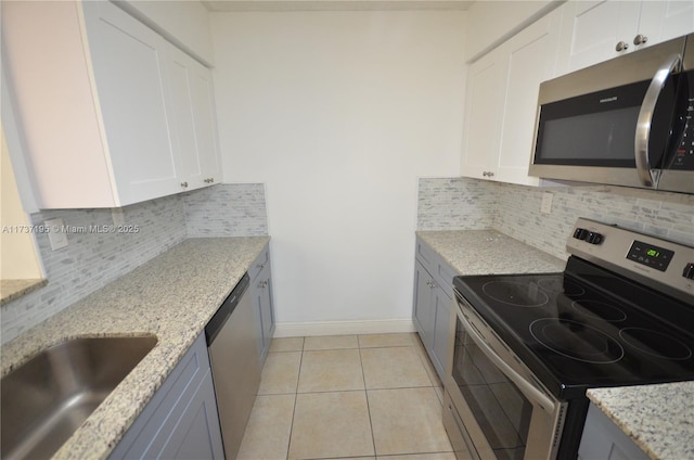 kitchen featuring stainless steel appliances, white cabinets, a sink, and baseboards