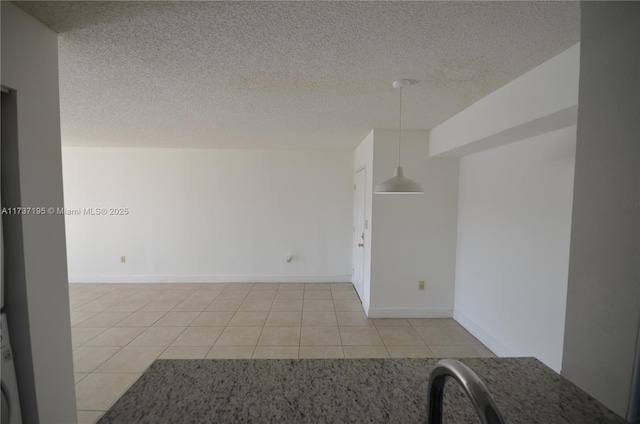 unfurnished room with light tile patterned floors, baseboards, and a textured ceiling