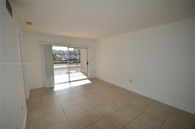 spare room with light tile patterned floors and baseboards