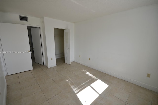 unfurnished bedroom featuring light tile patterned floors, baseboards, visible vents, and a closet