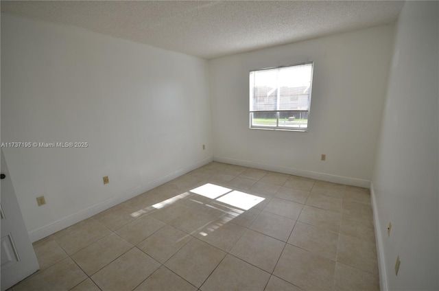 unfurnished room featuring light tile patterned floors, baseboards, and a textured ceiling