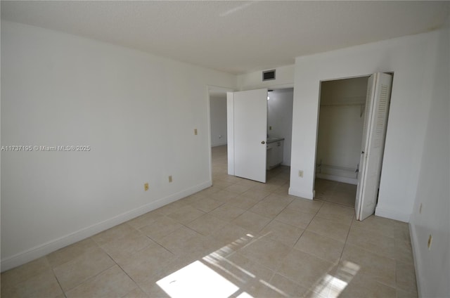 unfurnished bedroom with light tile patterned floors, a closet, visible vents, and baseboards