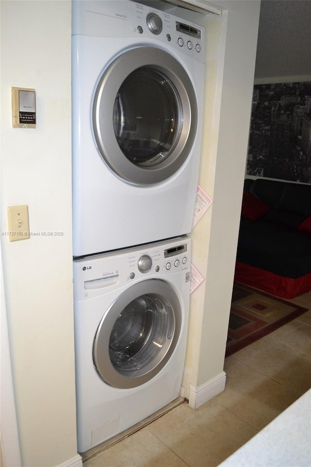 washroom with tile patterned floors, laundry area, and stacked washer and clothes dryer