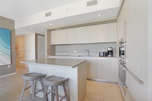 kitchen featuring sink, a center island, stainless steel oven, and a breakfast bar