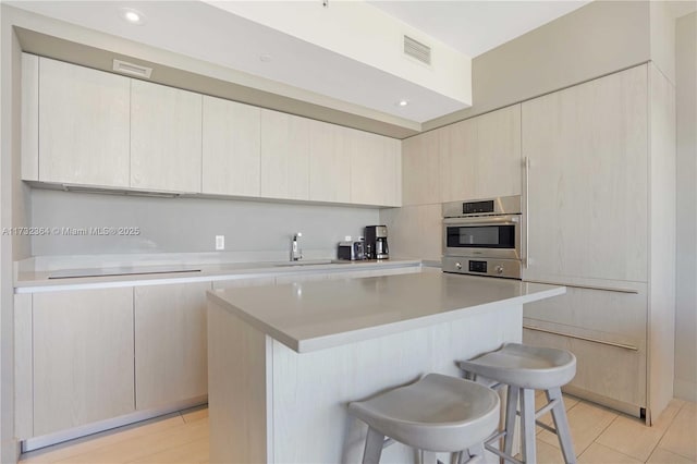 kitchen featuring a kitchen island, sink, light tile patterned floors, and a kitchen breakfast bar