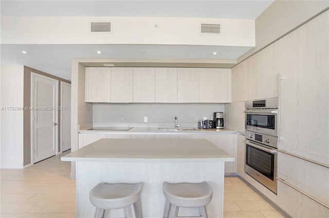 kitchen featuring light tile patterned flooring, sink, a breakfast bar area, a center island, and stainless steel double oven