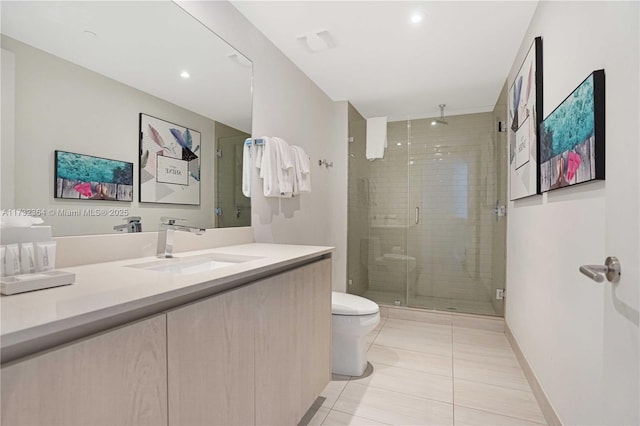 bathroom featuring tile patterned flooring, vanity, a shower with shower door, and toilet