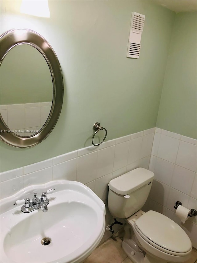 bathroom with tile walls, sink, tile patterned floors, and toilet