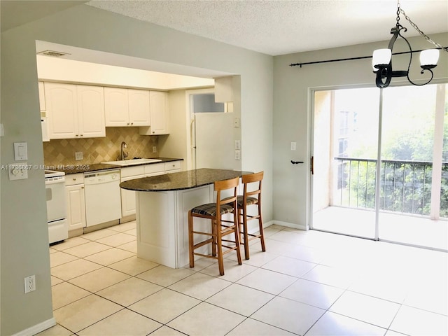 kitchen featuring sink, a breakfast bar area, white cabinets, hanging light fixtures, and white appliances