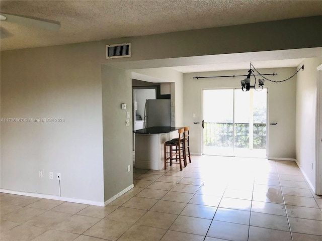 unfurnished room with light tile patterned flooring, a notable chandelier, and a textured ceiling