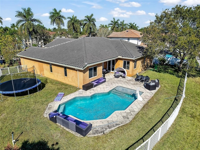 view of pool with outdoor lounge area, a patio area, a trampoline, and a lawn