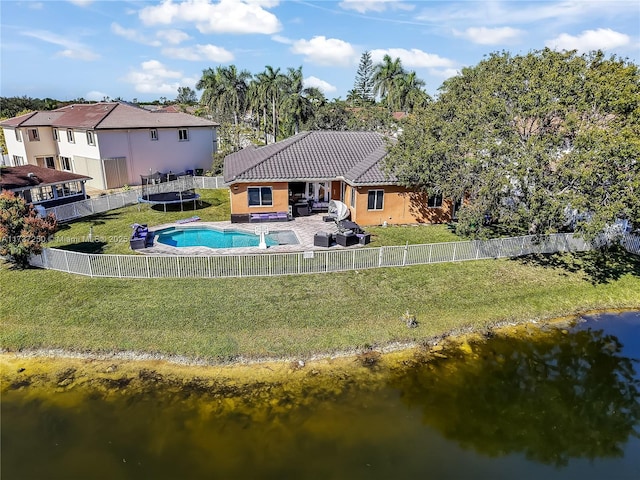 back of property featuring a fenced in pool, a yard, an outdoor living space, and a water view