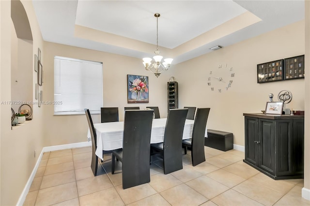 dining space featuring light tile patterned flooring, a chandelier, and a tray ceiling