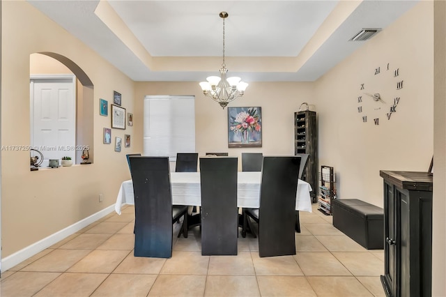 dining area with a notable chandelier, a tray ceiling, and light tile patterned floors