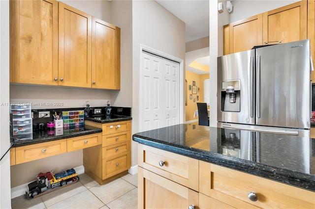 kitchen featuring dark stone countertops, stainless steel fridge with ice dispenser, and light tile patterned floors