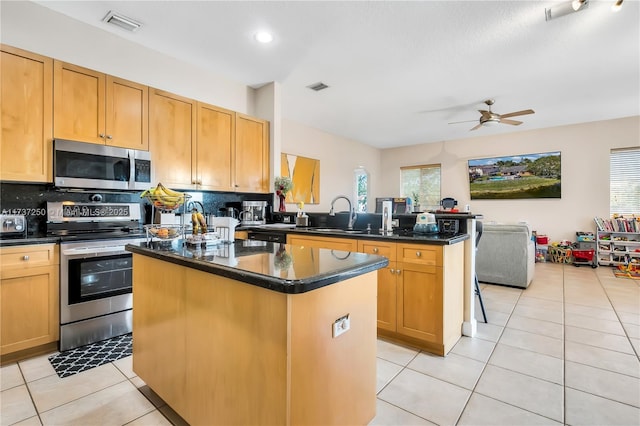 kitchen with backsplash, stainless steel appliances, a kitchen island, and light tile patterned floors