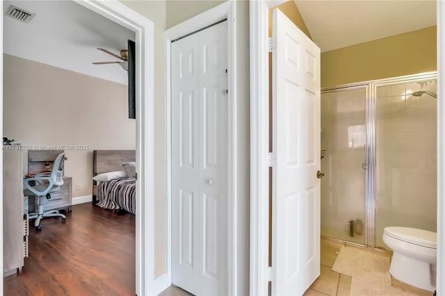 bathroom featuring walk in shower, lofted ceiling, toilet, ceiling fan, and tile patterned flooring