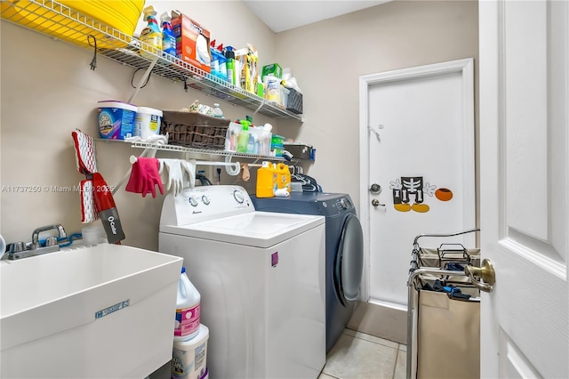 washroom with light tile patterned flooring, sink, and washing machine and clothes dryer