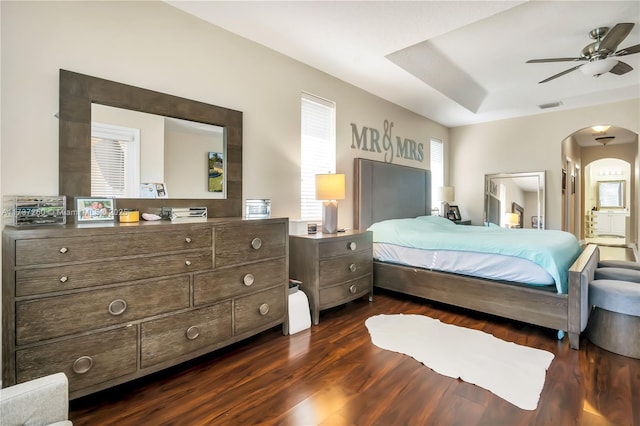 bedroom featuring a raised ceiling, dark wood-type flooring, and ceiling fan