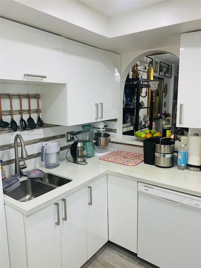 kitchen featuring white dishwasher, sink, white cabinetry, and tasteful backsplash