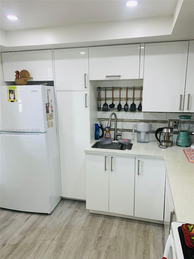 bar with sink, light hardwood / wood-style flooring, white cabinetry, stove, and white refrigerator