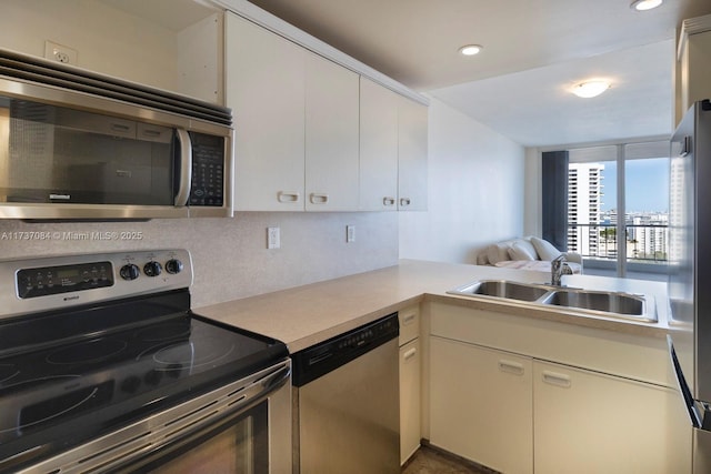 kitchen with tasteful backsplash, sink, white cabinets, kitchen peninsula, and stainless steel appliances