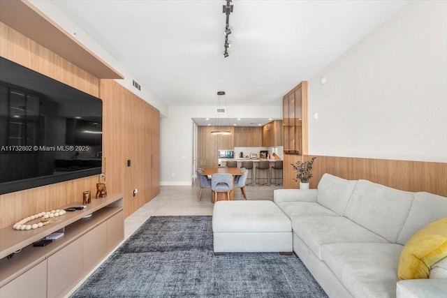 living room with track lighting and wood walls