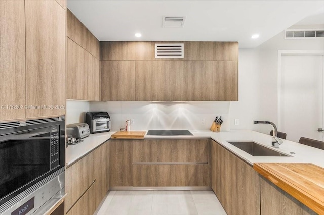 kitchen with built in microwave, butcher block counters, sink, stainless steel oven, and black electric cooktop