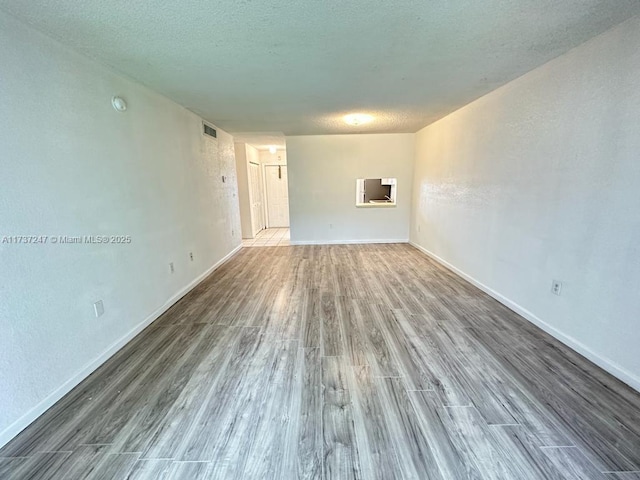 unfurnished room with wood-type flooring and a textured ceiling