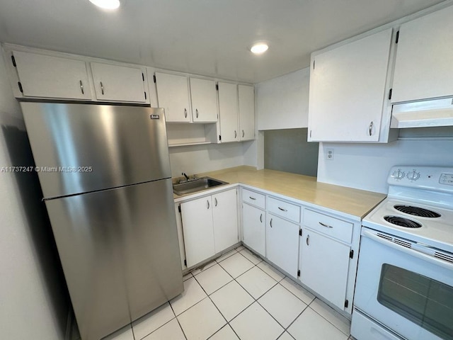 kitchen featuring light tile patterned flooring, sink, stainless steel refrigerator, electric stove, and white cabinets