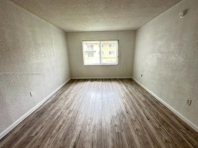 unfurnished room with hardwood / wood-style flooring and a textured ceiling