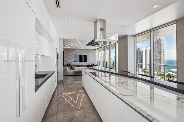 kitchen featuring sink, white cabinetry, island range hood, black electric stovetop, and light stone countertops