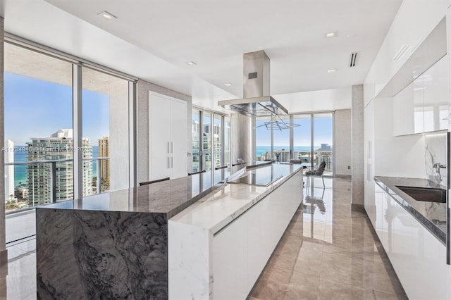 kitchen with black electric cooktop, island range hood, white cabinets, and a water view