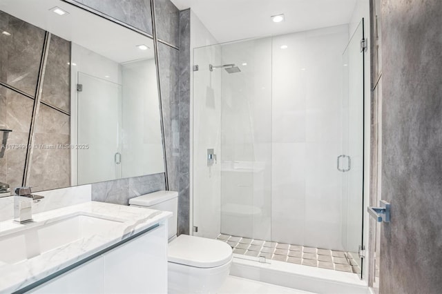 bathroom with vanity, a shower with door, toilet, and tile walls