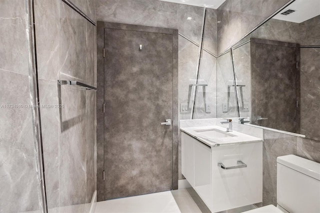 bathroom with vanity, tile walls, and toilet