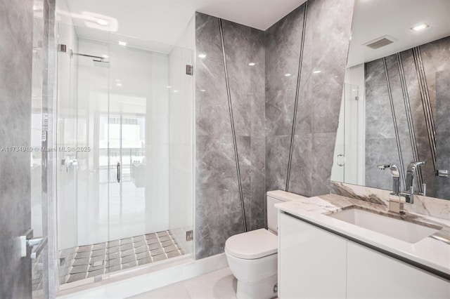 bathroom featuring vanity, toilet, a shower with door, and tile walls