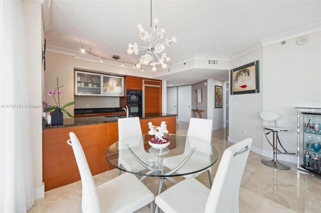 dining space with a notable chandelier, ornamental molding, and sink