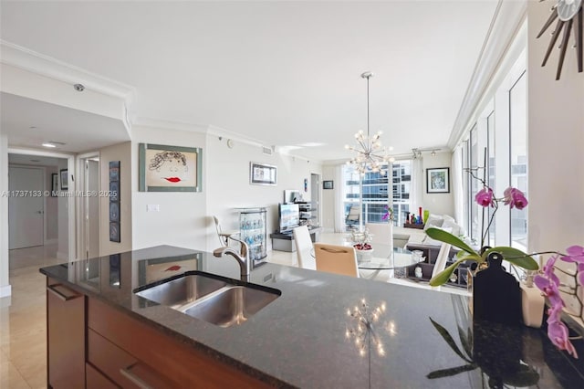 kitchen with sink, decorative light fixtures, ornamental molding, and dark stone counters