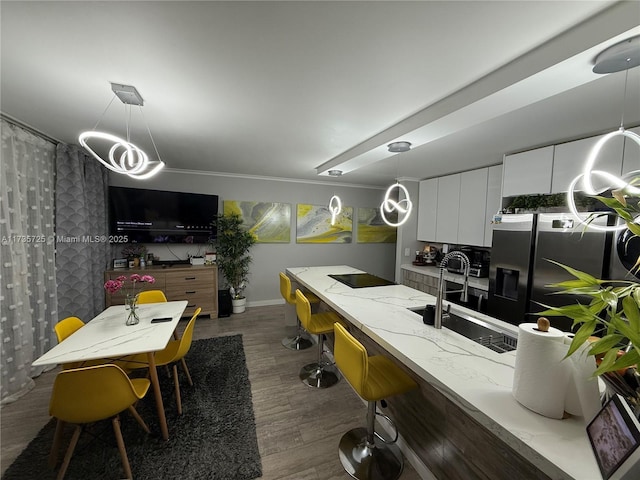 kitchen featuring dark wood-type flooring, sink, pendant lighting, light stone countertops, and white cabinets