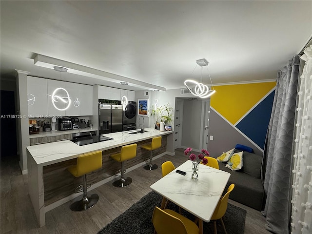 kitchen with pendant lighting, black electric stovetop, stainless steel fridge, and white cabinets