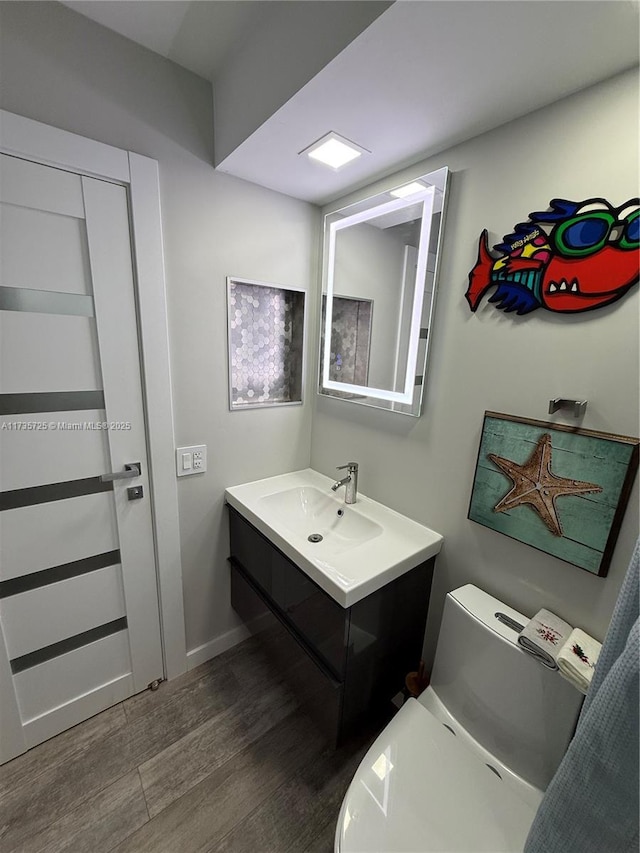 bathroom featuring vanity, wood-type flooring, and toilet