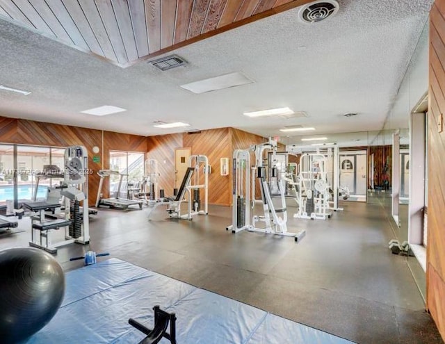 exercise room featuring wooden walls and a textured ceiling