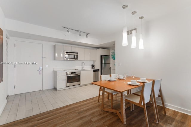 dining room featuring track lighting, wood-type flooring, and sink