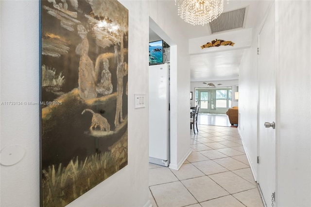 corridor featuring an inviting chandelier and light tile patterned floors