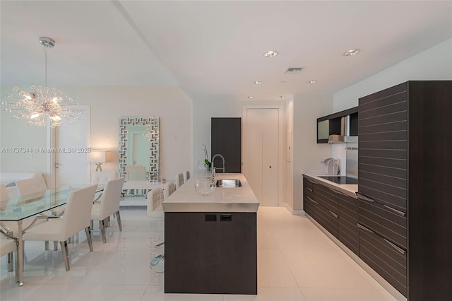 kitchen featuring light tile patterned flooring, sink, hanging light fixtures, and a center island with sink